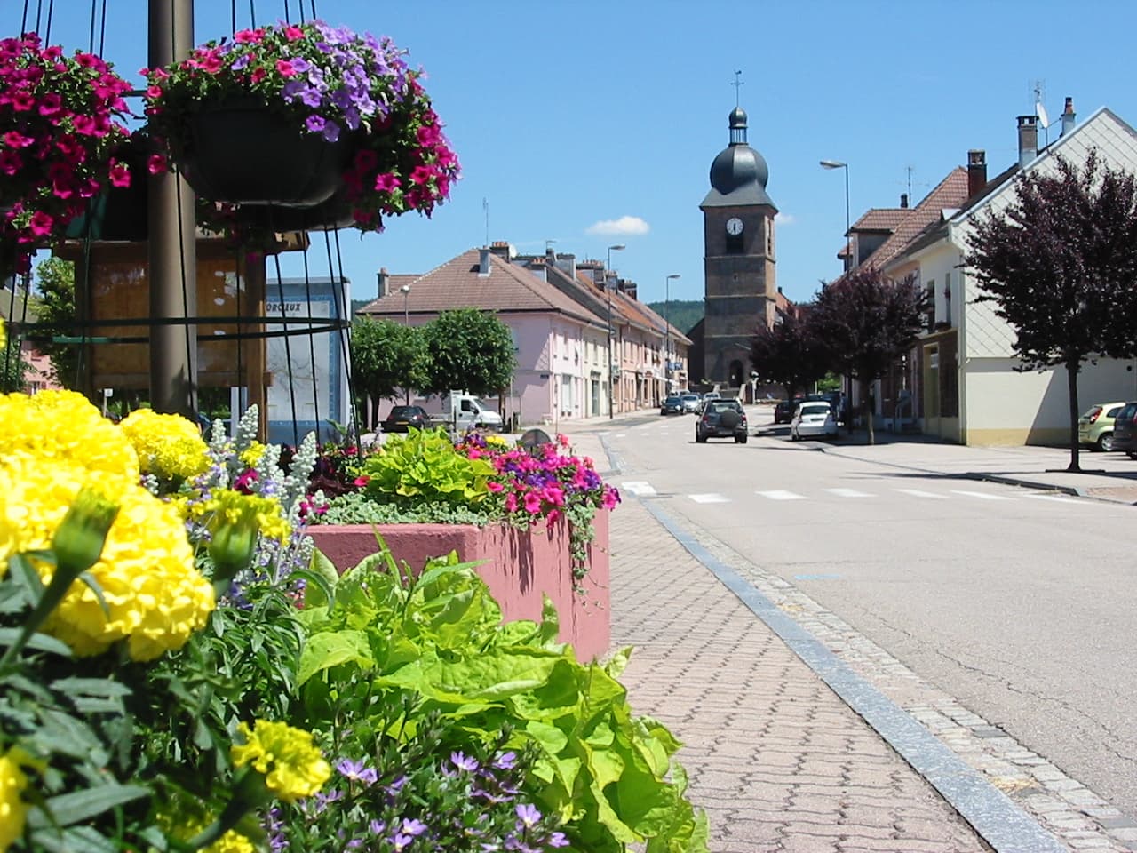 Rue fleurie de Corcieux avec le clocher du village
